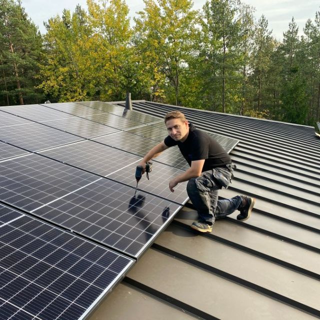 Työmies asentaa aurinkopaneelia