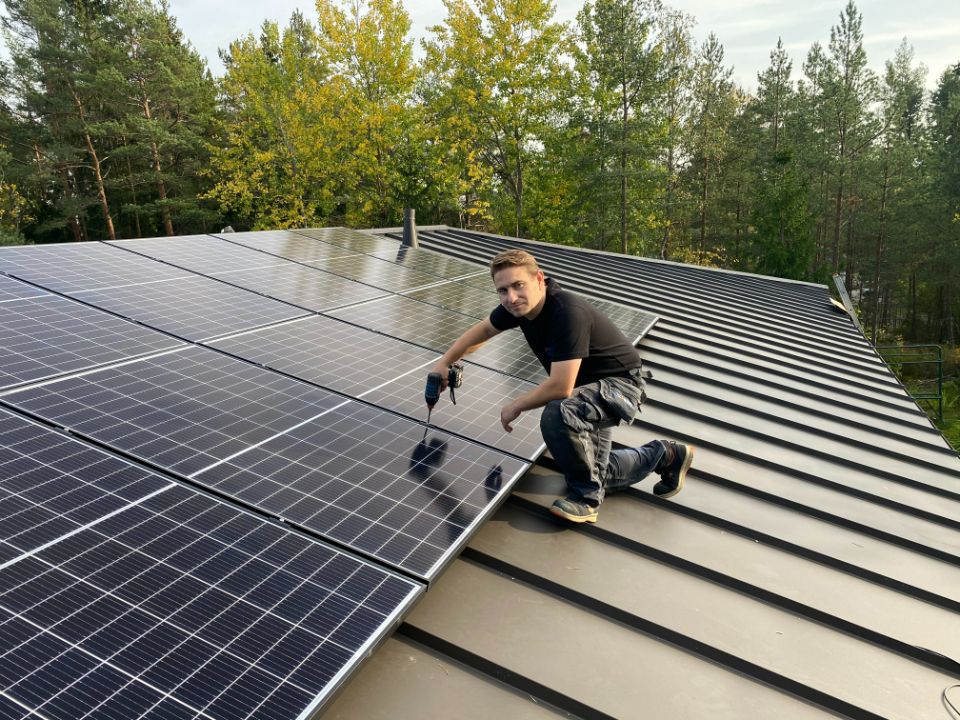 Työmies asentaa aurinkopaneelia